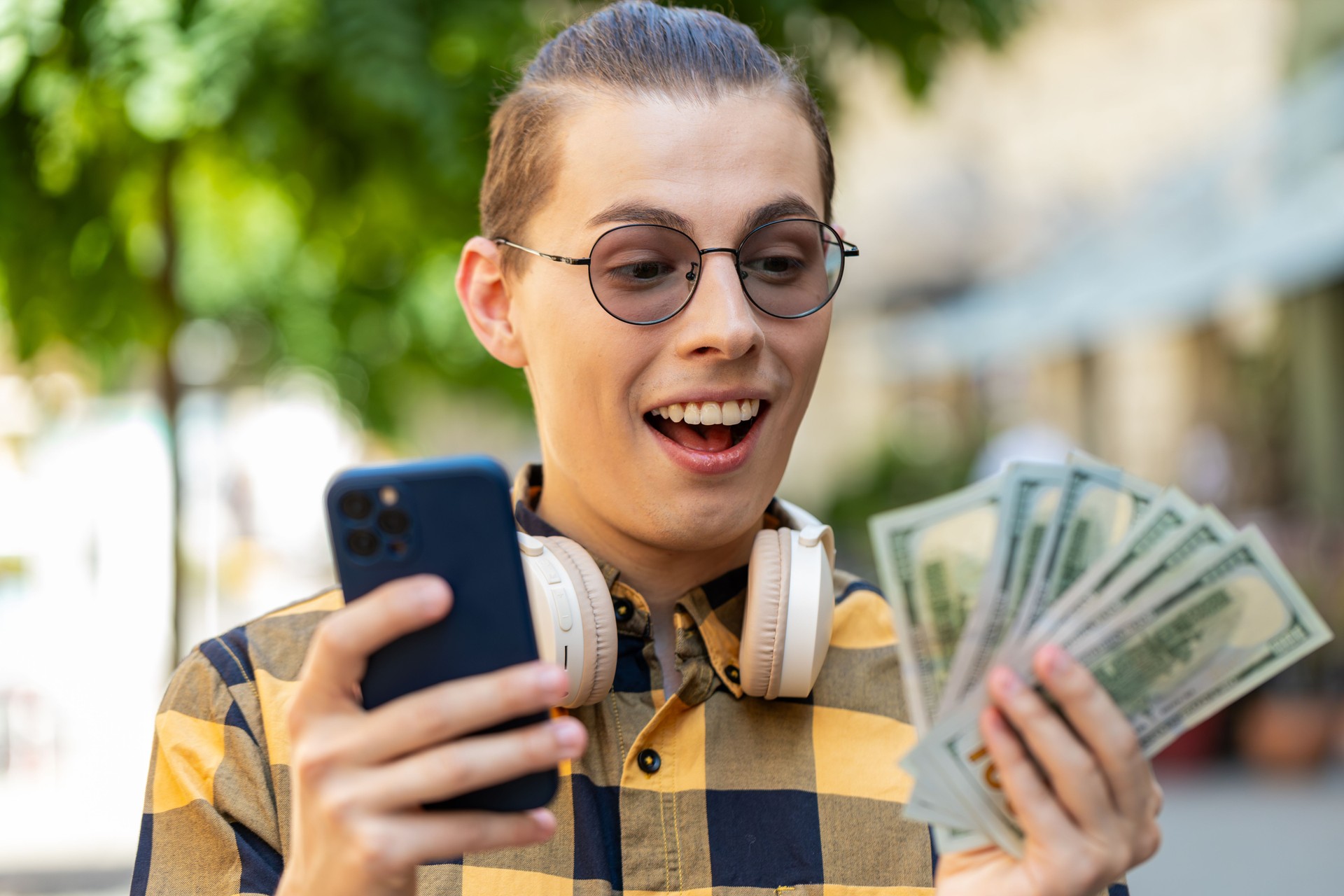 Happy rich man counting holding money dollar cash use smartphone mobile calculator app online order